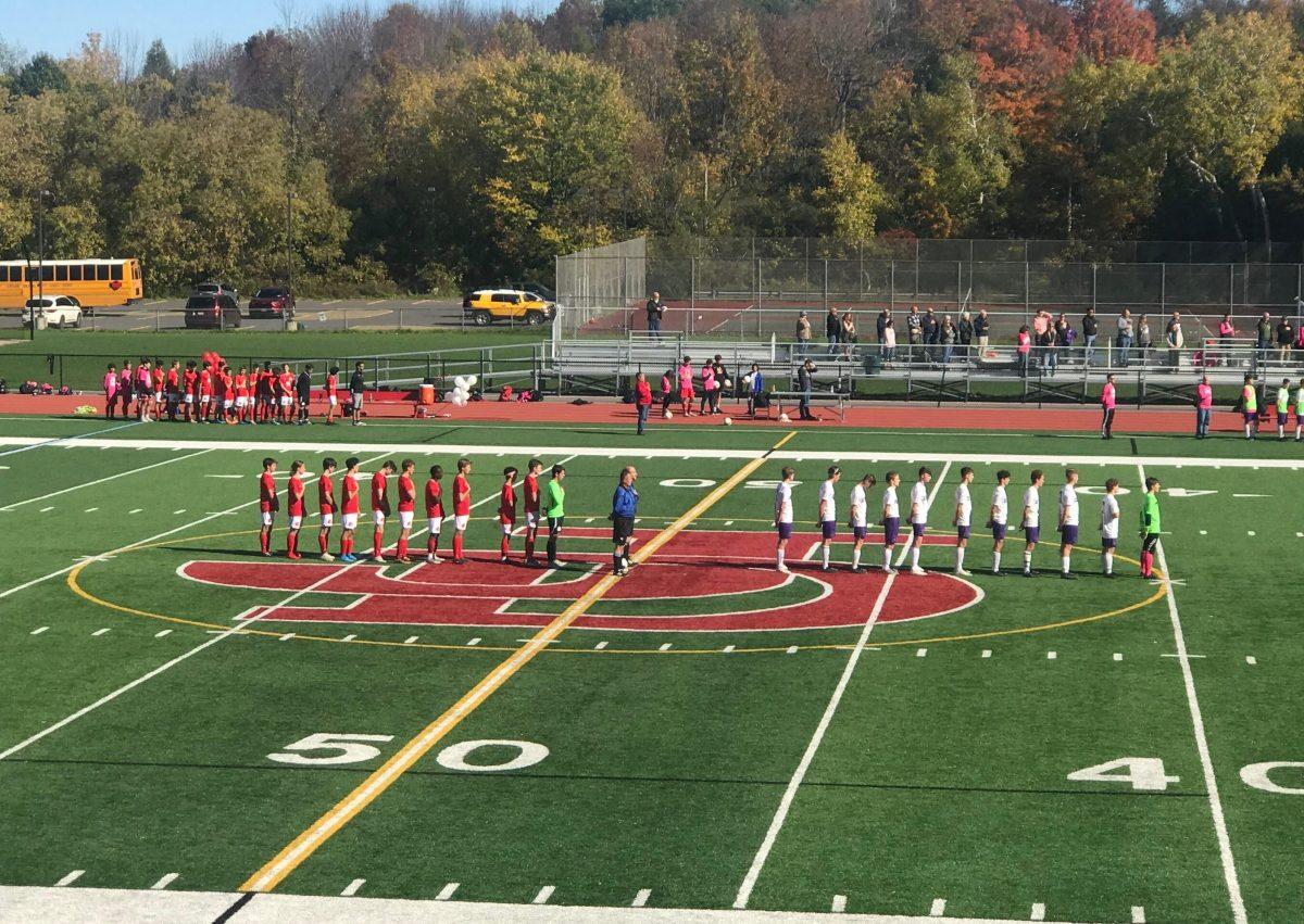 Both soccer teams line up as the National Anthem plays.
